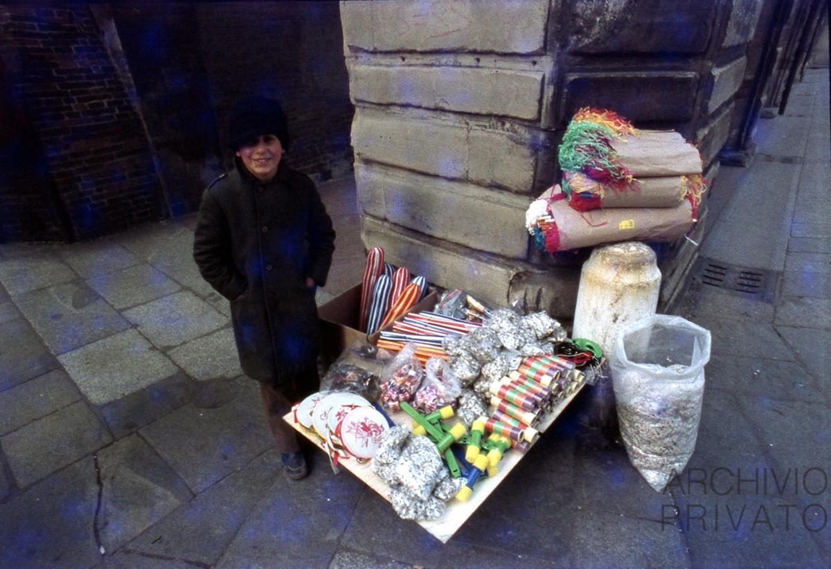 Bologna. Piazza Maggiore. Bambino al fianco di un banchetto di Carnevale